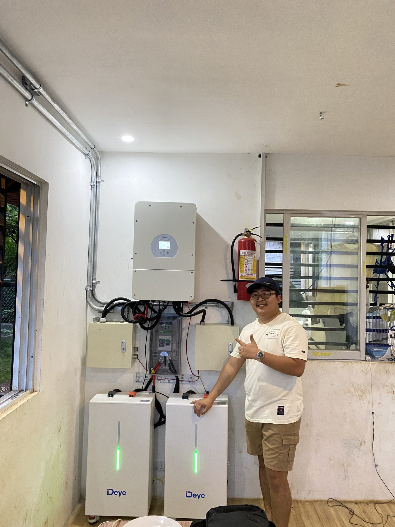 Technician beside the completed 12 kW inverter and battery set