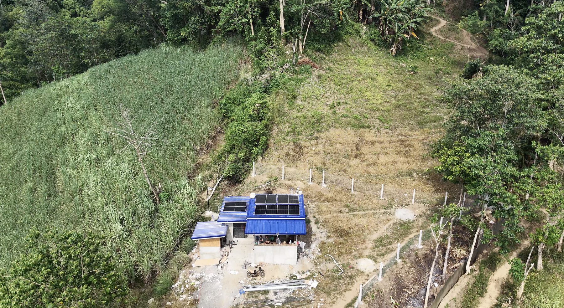 Aerial view of an off-grid farm house with rooftop solar panels surrounded by farmland