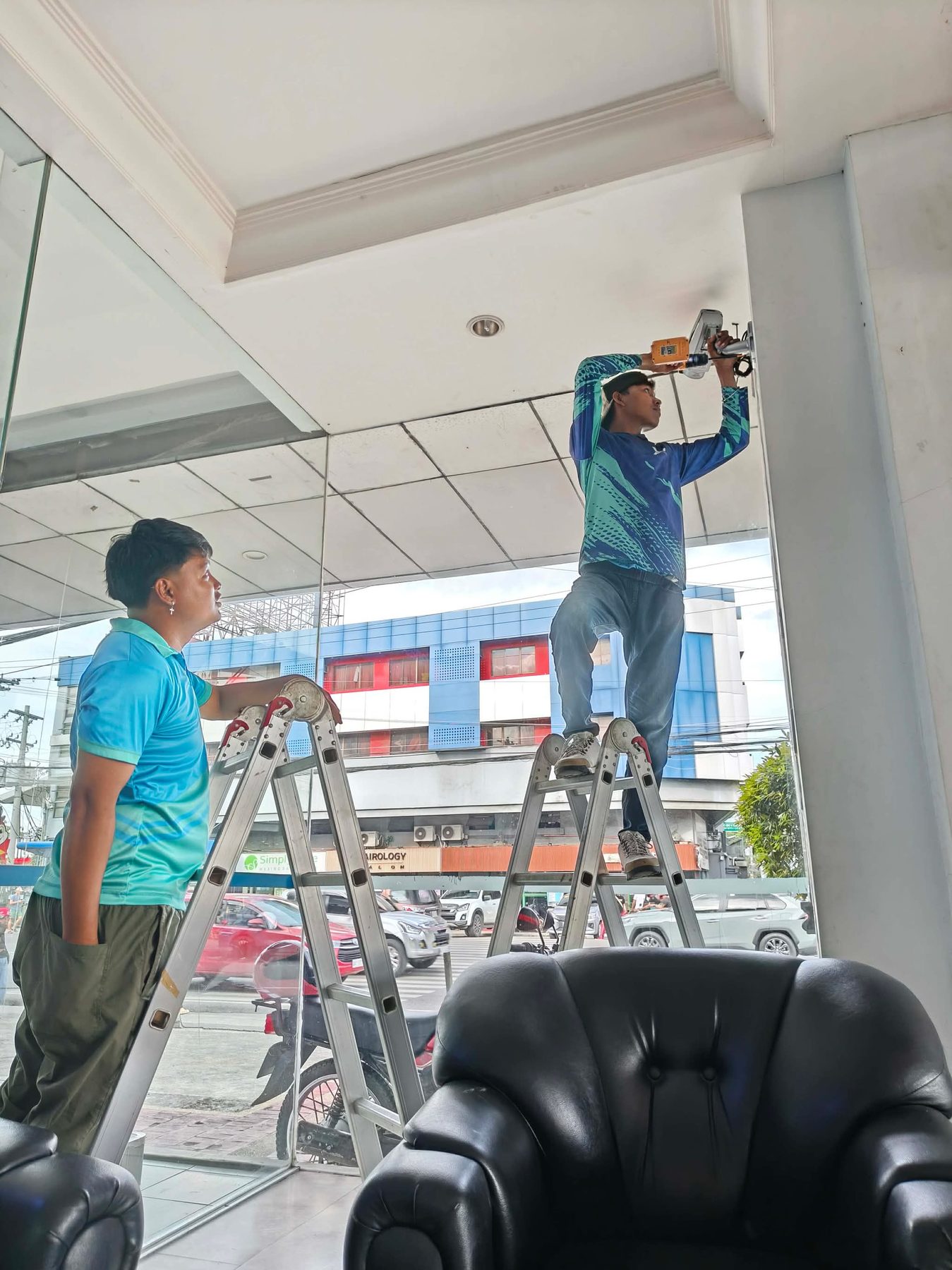 Technicians on ladders mounting a camera at the Panasonic Davao showroom