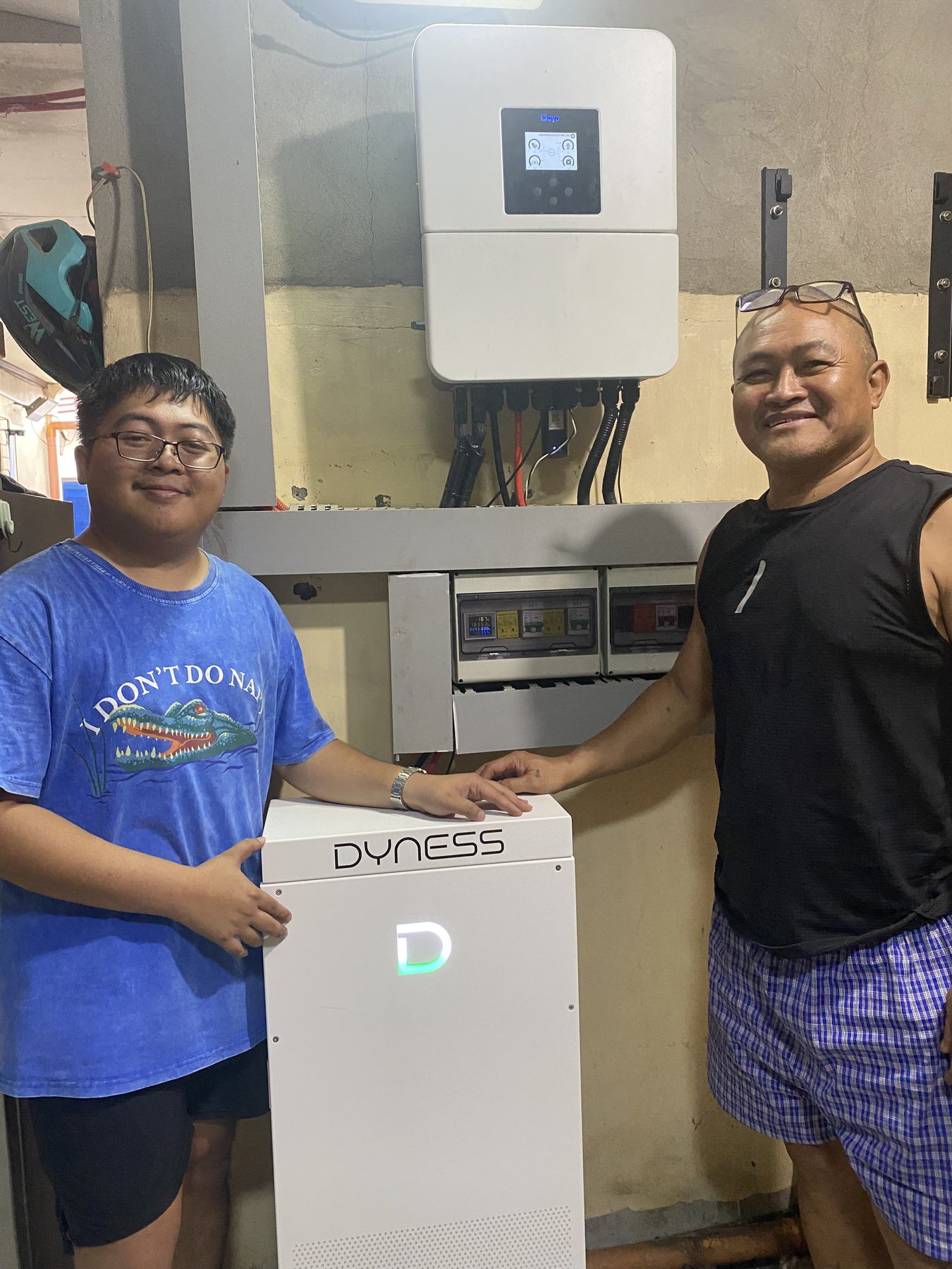 Technician and homeowner beside the new inverter and battery
